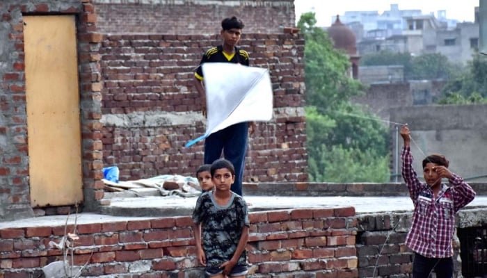 Children enjoy kite flying on the rooftop near the Do Moria Pul, Lahore, Punjab, July 25, 2024. — APP