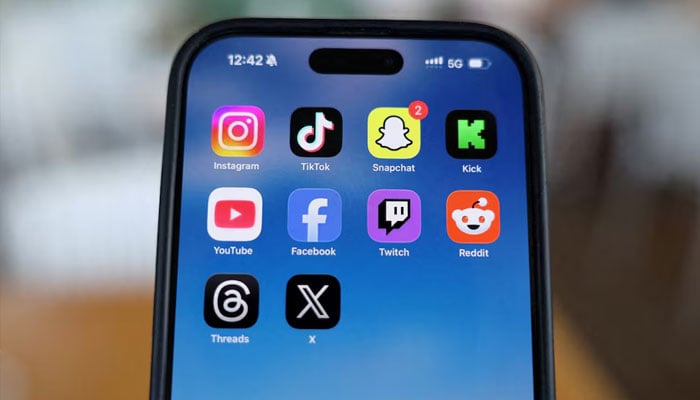Instagram, TikTok, Snapchat, Kick, YouTube, Facebook, Twitch, Reddit, Threads, and X applications are displayed on a mobile phone in this picture illustration taken on December 9, 2025. — Reuters