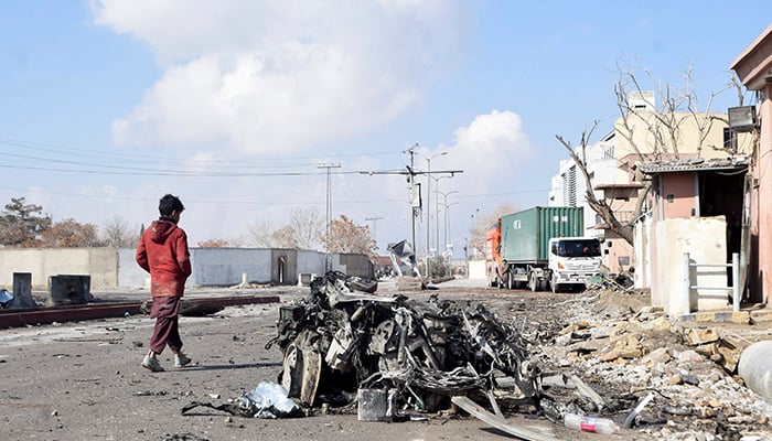 A person walks past the remains of a damaged vehicle at a site, after militant attacks, in Quetta, February 1, 2026. — Reuters