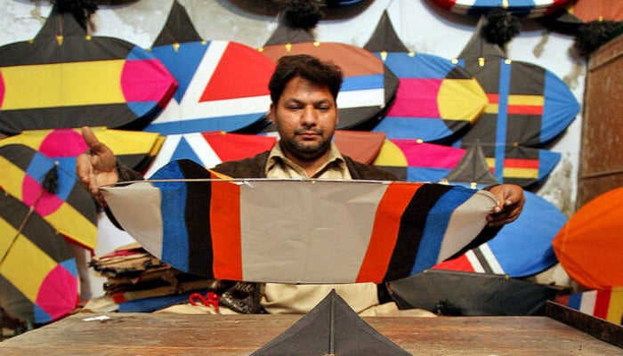A shopkeeper makes new kites at a kite shop in Lahore, 18 February 2007. — Reuters