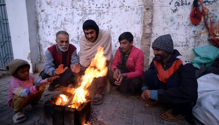 People warm their hands at bonfire to keep themselves safe from cold weather in Safdar, Karachi, on January 23, 2026. — PPI