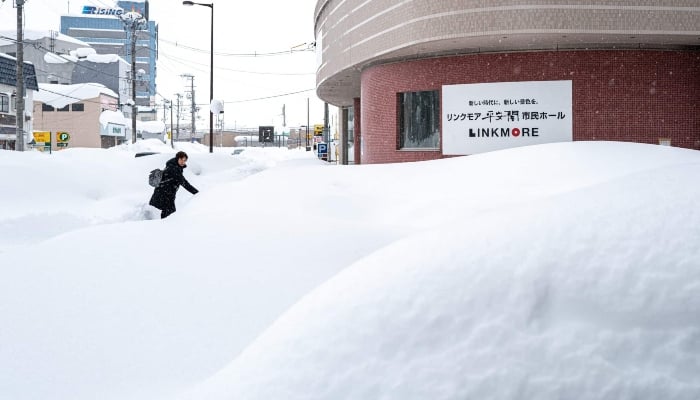 A pedestrian walks on the snow covered pavement in Aomori city, Aomori prefecture on January 30, 2026. — AFP