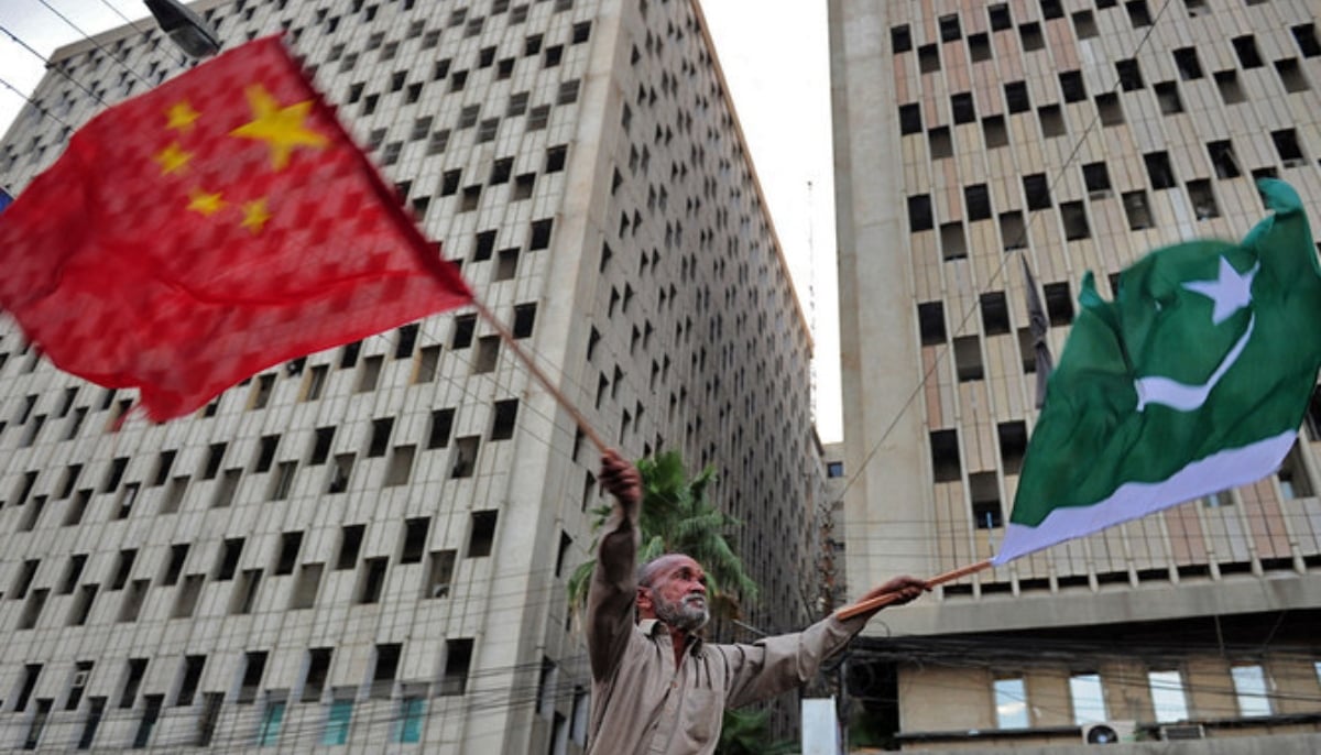 A Pakistani man waves Pakistani and Chinese national flags on a street of Karachi. — AFP/File