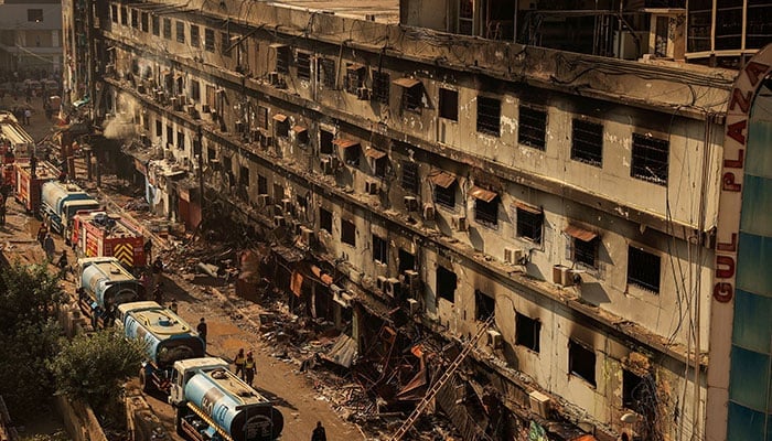 Fire department workers walk past the site, following a massive fire that broke out in the Gul Plaza shopping centre in Karachi on January 20, 2026. — Reuters