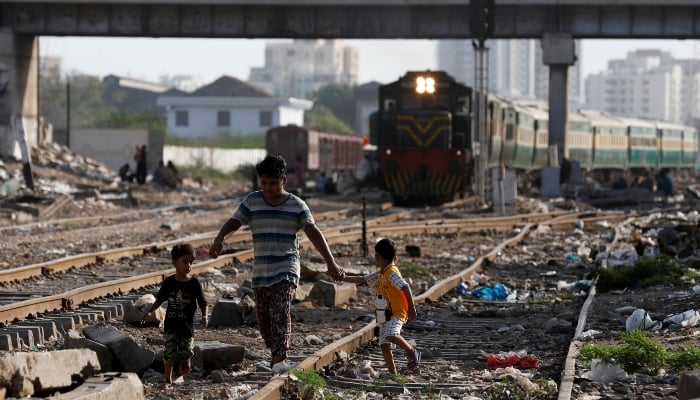 Siblings walk along a railway tracks at a slum area in Karachi, July 9, 2020. — Reuters