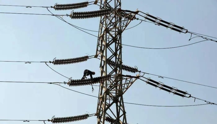 A technician works on porcelain insulators on power transmission tower in Karachi. — Reuters/File