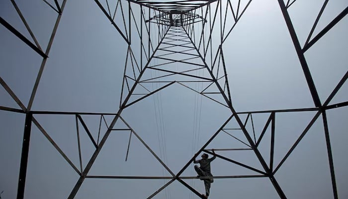 A worker of Peshawar Electric Supply Company (PESCO) climbs up a high-voltage pylon in Peshawar, Pakistan, August 7, 2017. — Reuters