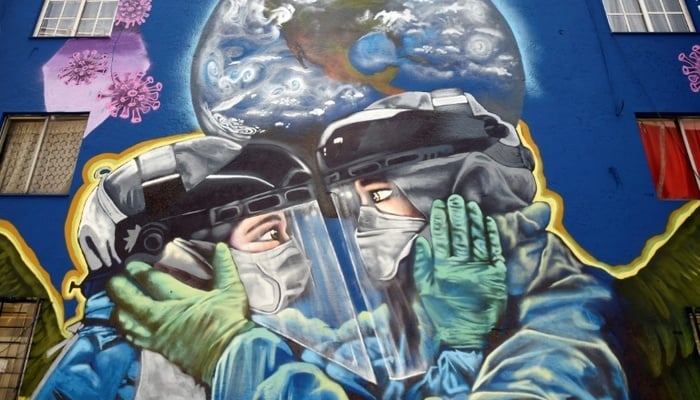 A wall graffiti shows two healthcare providers dressed in protective gear. —  AFP
