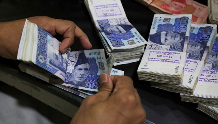 A man counts rupee notes at a currency exchange shop in Peshawar on September 12, 2023. — Reuters