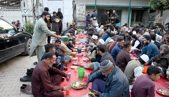 A large number of people break their fast at a free Iftar arrangement along the roadside at I-9 sector in Islamabad, March 19, 2025. — APP