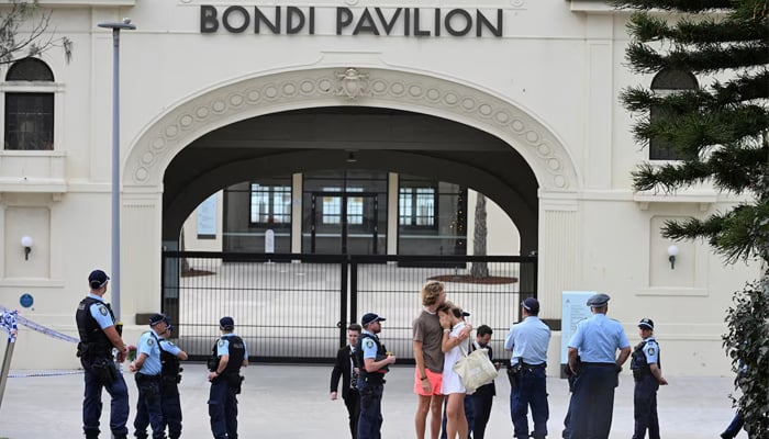Two people embrace as police officers stand guard outside Bondi Pavilion following the attack on a Jewish holiday celebration at Sydneys Bondi Beach, in Sydney, Australia, December 15, 2025. — Reuters