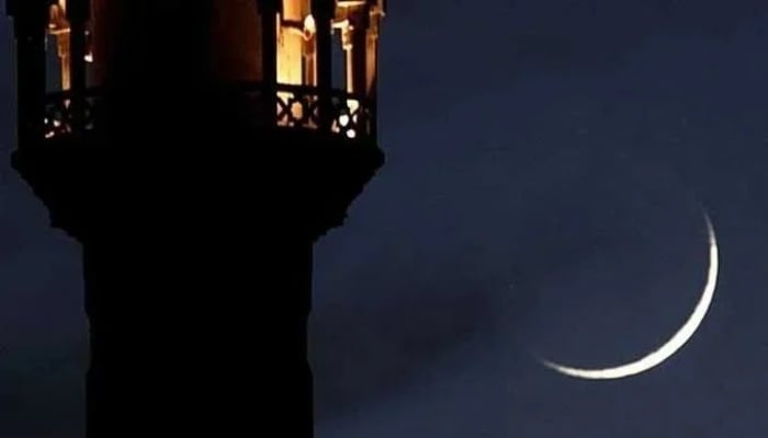 A new crescent seen through a telescope shines beside the tower of a mosque. — Reuters/File