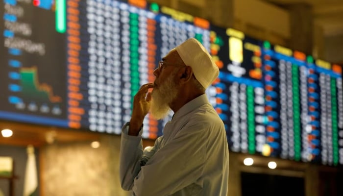 A stockbroker reacts while monitoring the market on the electronic board displaying share prices during a trading session at the Pakistan Stock Exchange, in Karachi, July 3, 2023. — Reuters