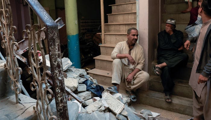 Residents sit beside debris after a gas cylinder blast caused a portion of a residential building to collapse in Karachi on February 19, 2026. — Reuters