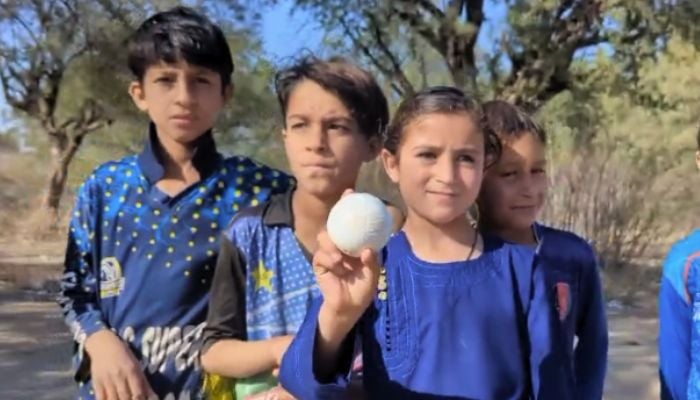 Eight-year-old Aena Wazir from North Waziristan, KP, holds a taped ball while posing for a picture with her friends. — Geo News