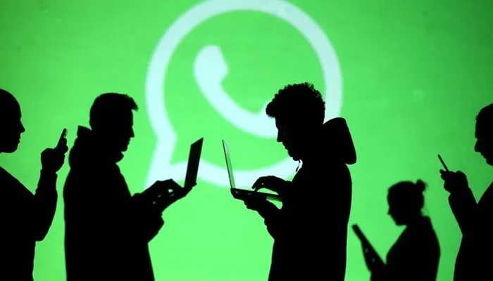 Silhouettes of laptop and mobile device users are seen next to a screen projection of Whatsapp logo in this picture illustration taken March 28, 2018. — Reuters