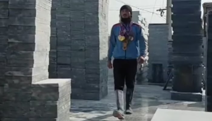 National-level martial arts and gymnastics athlete Rizwan Pathan, wearing his medals, walks at the marble factory where he works. — Screengrab via Geo News
