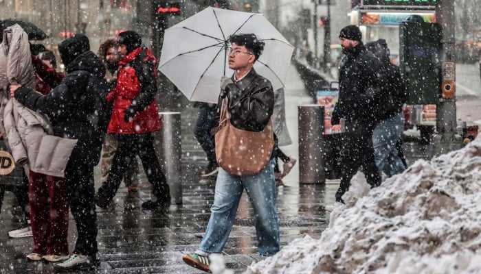 People walk on a street as snow falls during a winter storm in New York City, US, February 22, 2026. — Reuters