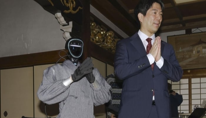 Seiji Kumagai, professor at Kyoto University, stands next to a humanoid monk robot in Kyoto, western Japan, on Feb. 24, 2026. — Kyodo News