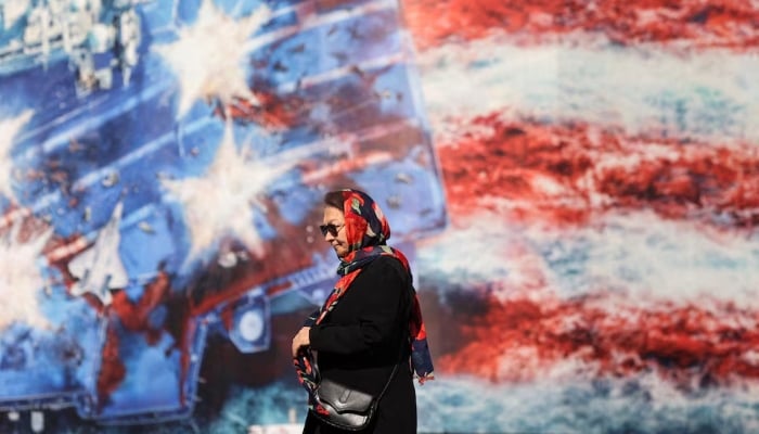 An Iranian woman walks past an anti-U.S. billboard in Tehran, Iran, February 26, 2026