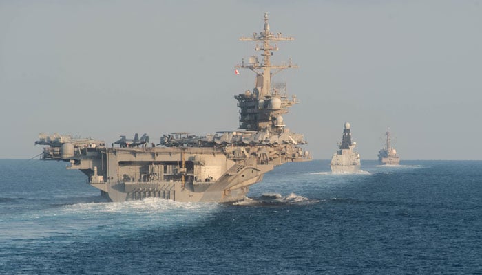 The USS Abraham Lincoln aircraft carrier (L) transits the Strait of Hormuz. — AFP/File