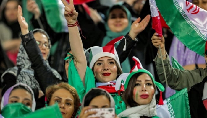Women football fans wave national flags and cheer during a friendly match between Iran and Kenya in Tehran. — AFP/File