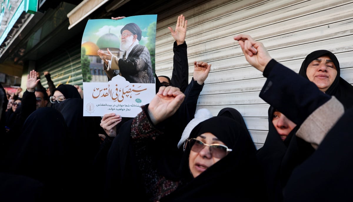 A woman holds a poster with the picture of Irans Supreme Leader Ayatollah Ali Khamenei as people gather after Khamenei was killed in Israeli and US strikes on Saturday, in Tehran, Iran, March 1, 2026. — Reuters