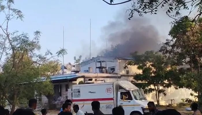 Plumes of dark smoke rise as stunned bystanders survey the aftermath. — NDTV