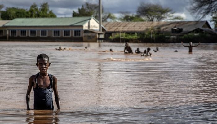 A boy stands in floodwaters at an inundated area in Kenya in 2023. — AFP