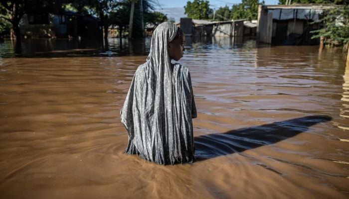 A woman wades through floodwaters at an inundated residential area in Garissa, Kenya, on May 9, 2024. — AFP