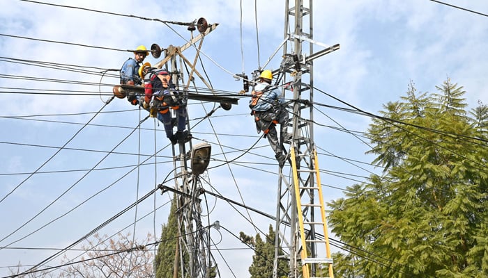 IESCO staffers repair electricity wires on a pole to restore power in an affected area in Islamabad, on January 21, 2026. — APP