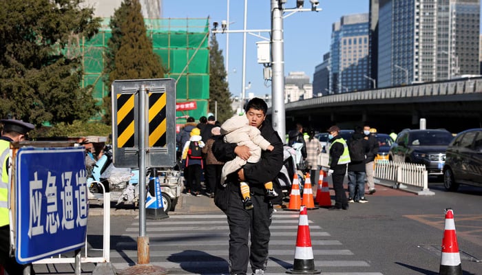 A man carries a child outside a childrens hospital in Beijing, China November 24, 2023. — Reuters