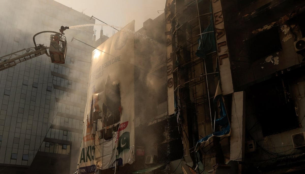 A firefighter works next to the smoldering remains, following a massive fire that broke out in the Gul Plaza Shopping Mall in Karachi on January 19, 2026. — Reuters