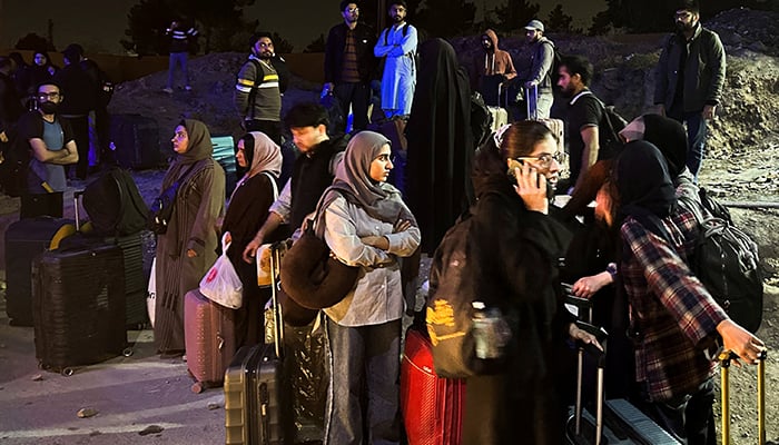Pakistani families and students stand with their belongings after returning from Iran following the US and Israeli strikes, in Quetta, Pakistan, March 3, 2026. — Reuters