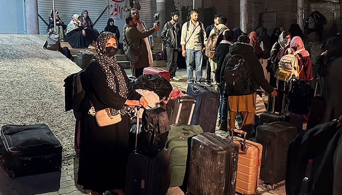 Pakistani families and students stand with their belongings after returning from Iran following the US and Israeli strikes, in Quetta, Pakistan, March 3, 2026. — Reuters