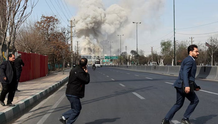People run as smoke rises following an explosion, amid the U.S.-Israeli conflict with Iran, in Tehran, Iran. — Reuters