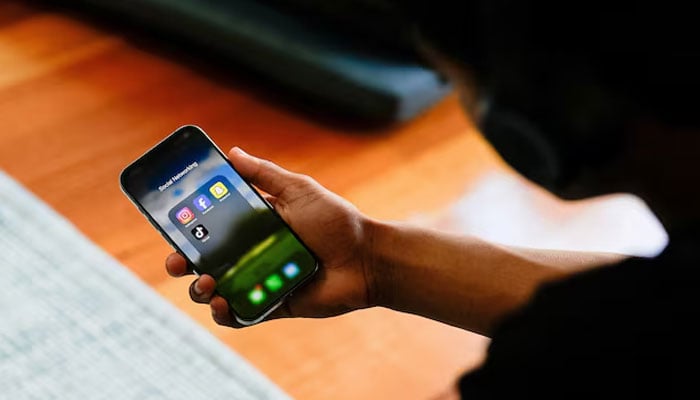A high school student poses with his mobile phone showing his social media applications. — Reuters/File