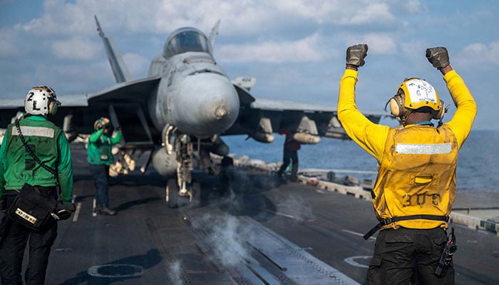 A US Navy sailor signals an F/A-18E Super Hornet on the flight deck of the Nimitz-class aircraft carrier USS Abraham Lincoln in support of the Operation Epic Fury attack on Iran at an undisclosed location on March 4, 2026. — Reuters