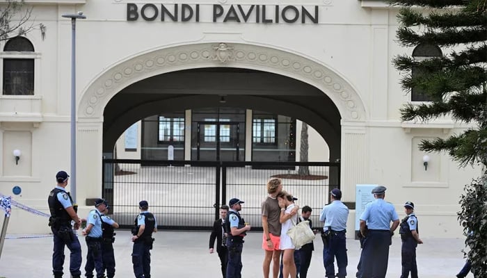Two people embrace as police officers stand guard outside Bondi Pavilion following the attack on a Jewish holiday celebration at Sydneys Bondi Beach, in Sydney, Australia, December 15, 2025. — Reuters