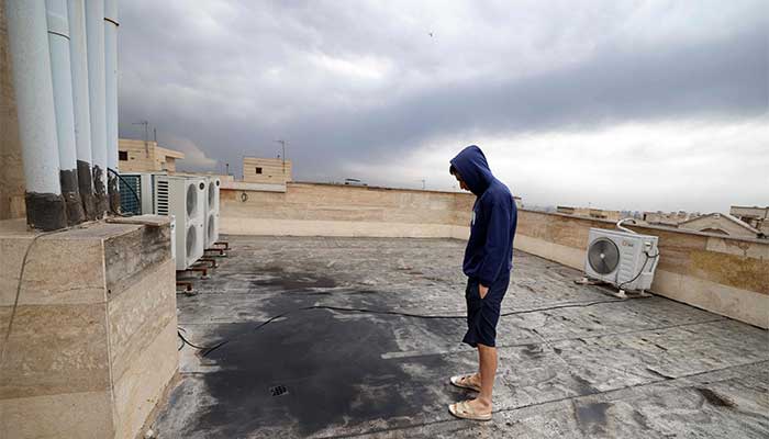A resident stands on the roof of his house covered with soot after overnight strike on the Tehran Oil Refinery in Tehran on March 8, 2026. — AFP