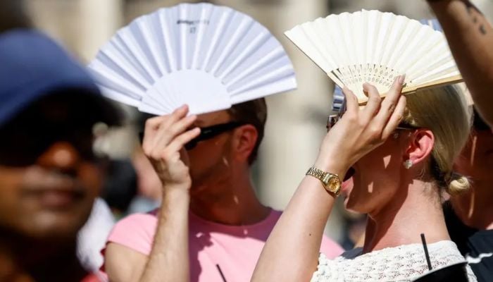 Tourists protect themselves with fans against the sun at Munichs Marienplatz square on June 29, 2025, in southern Germany. — AFP