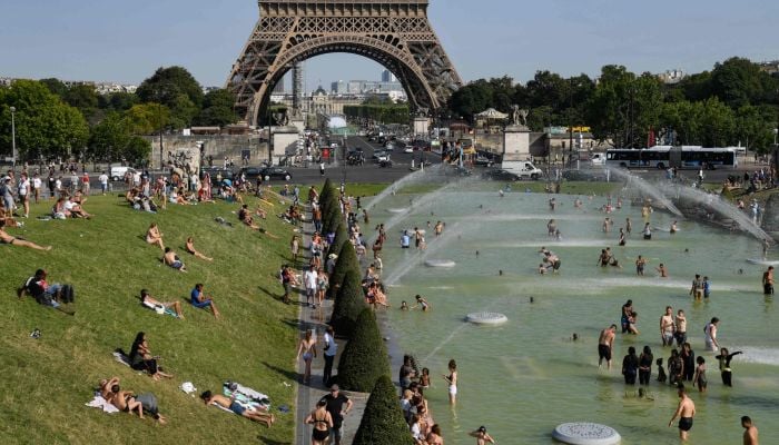 People cool off at the Trocadero Fountains next to the Eiffel Tower in Paris, on July 23, 2019 as a new heatwave hits Europe. — AFP