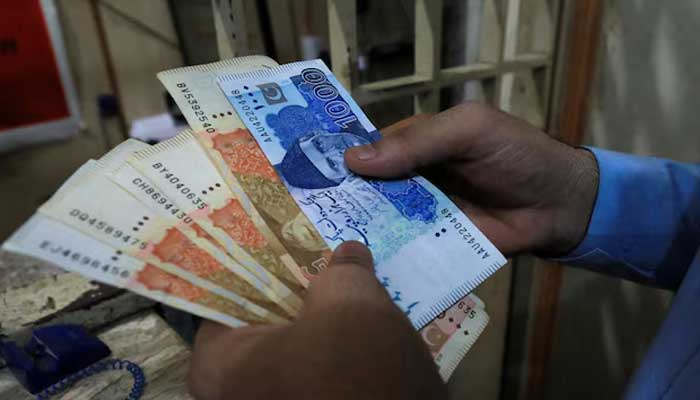 A man counts Pakistani rupee notes at a currency exchange shop in Peshawar, Pakistan September 12, 2023. — Reuters