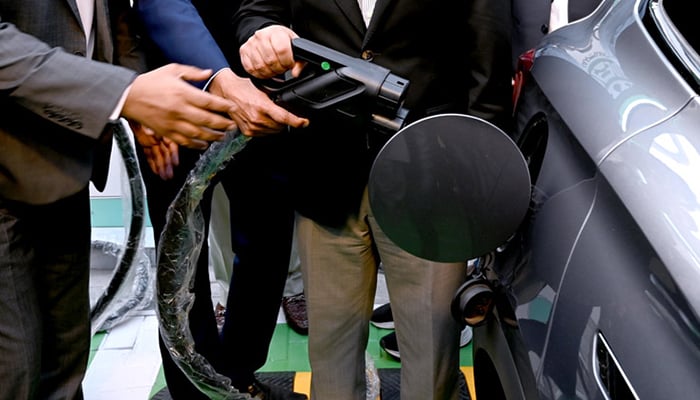 People charging an electric vehicle in Islamabad, on March 25, 2026. — APP