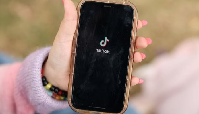 A girl poses while opening the TikTok app on her phone in Sydney, Australia, November 22, 2025. — Reuters