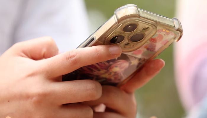 A girl uses her mobile phone after an interview discussing Australias social media ban for users under 16, which is scheduled to take effect on December 10, in Sydney, Australia, November 22, 2025. — Reuters