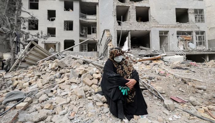 A woman sits outside her destroyed apartment after it was damaged by an airstrike while she was inside, amid the US-Israeli conflict with Iran, in Tehran, Iran, March 12, 2026. — Reuters