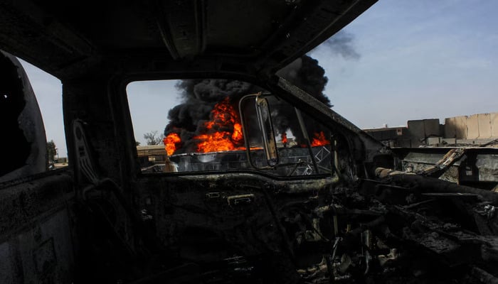Thick black smoke is seen through a destroyed truck at a fuel depot in Kandahar, Afghanistan, March 13, 2026. — Reuters
