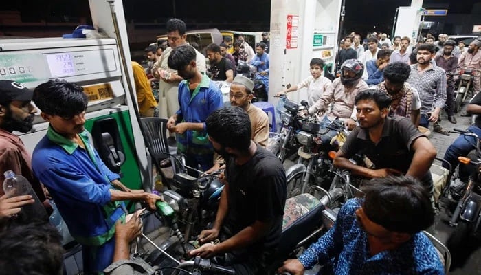 People wait their turn to get fuel at a petrol station in Karachi. — Reuters/File