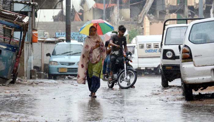 A woman holds an umbrella over her head to save himself from rain during the heavy downpour of monsoon season, at Korangi area in Karachi on June 28, 2025. — PPI